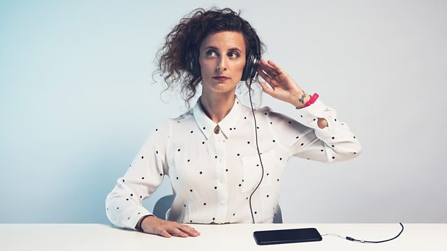Felicity Ward wearing headphones which are connected to her smartphone