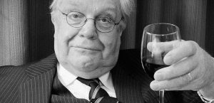 Sir Murray Rivers holding a glass of red wine