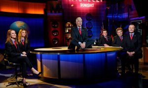 The cast of Shaun Micallef's Mad As Hell sitting on the set in identical suits