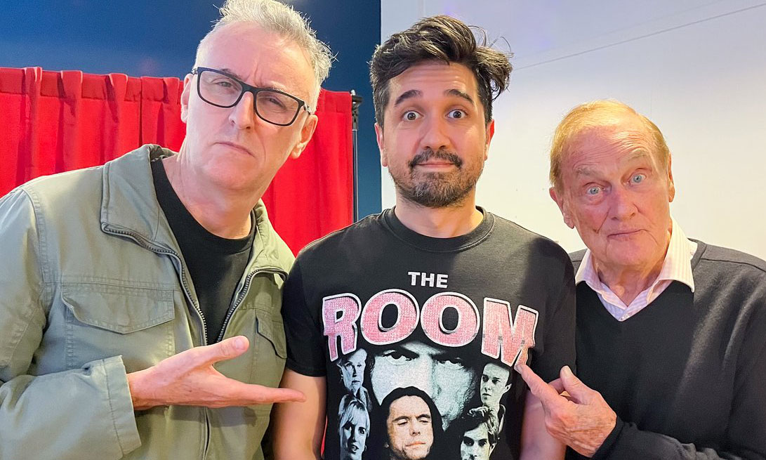 Tony Martin and Pete Smith pointing at Djovan Caro's The Room t-shirt