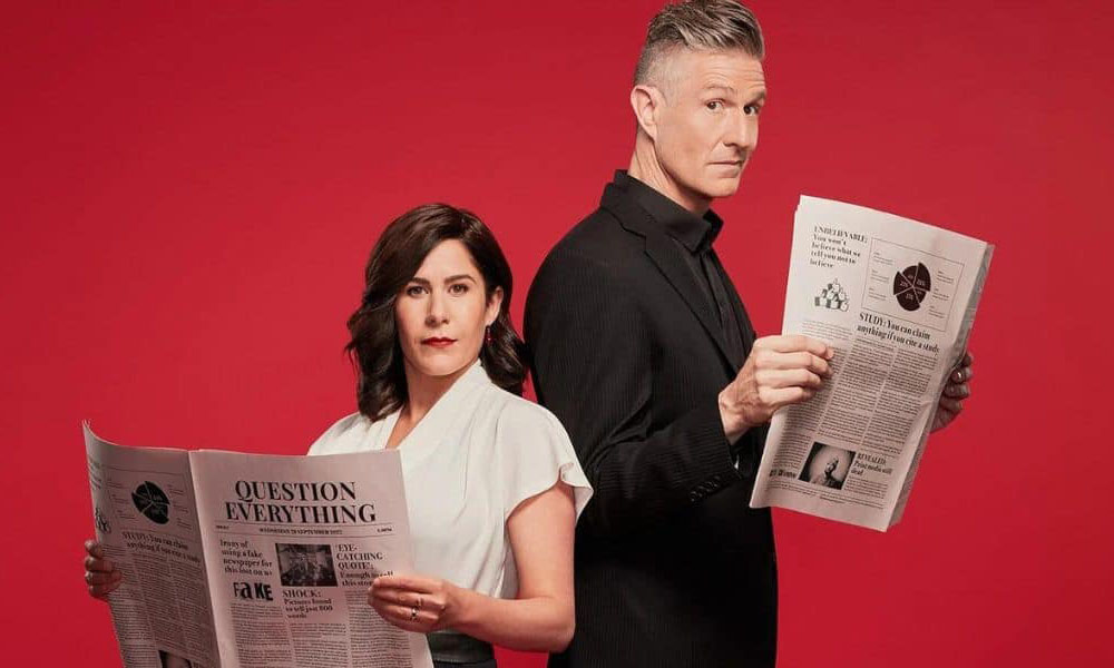 Jan Fran and Wil Anderson pose holding open newspapers