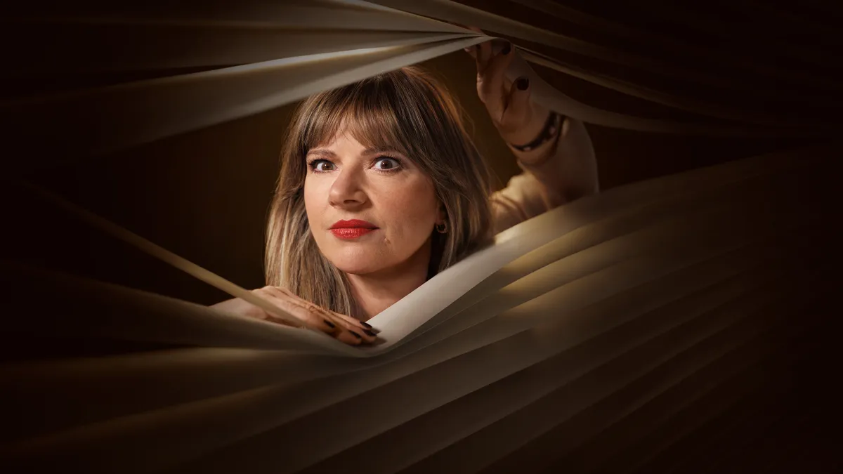 Julia Zemiro peeps through some Venetian blinds