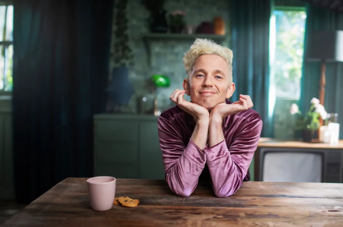 Mitch McTaggart sat happily at a table with a mug and some biscuits