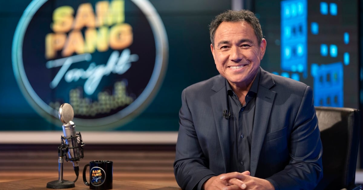 Sam Pang sat a desk with a mug and a microphone