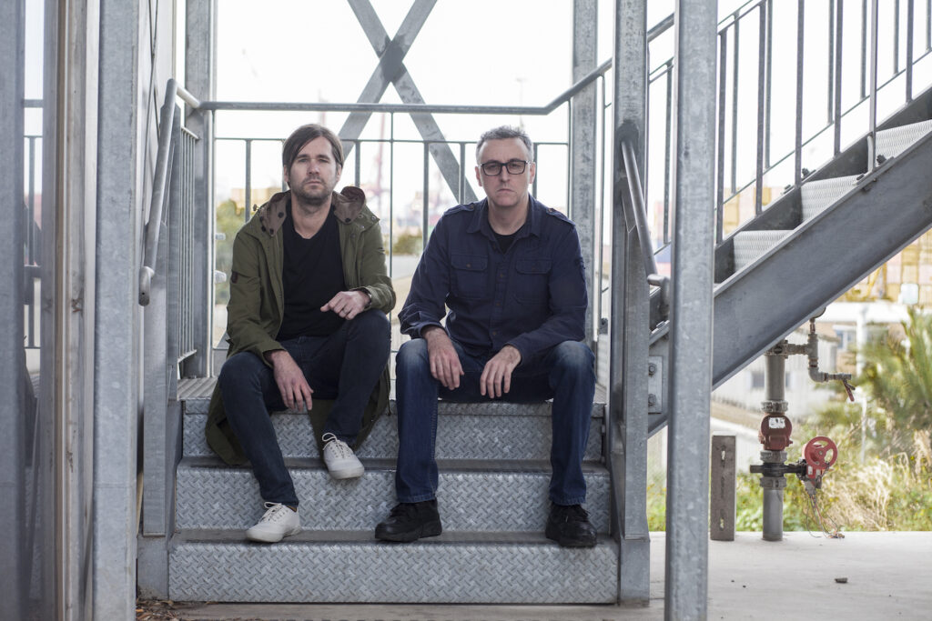Matt Dower and Tony Martin sitting on some metal stairs